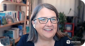 A woman with glasses and earbuds smiles while sitting indoors, with bookshelves and plants in the background. The logo "TACTICAL" appears in the lower right corner.
